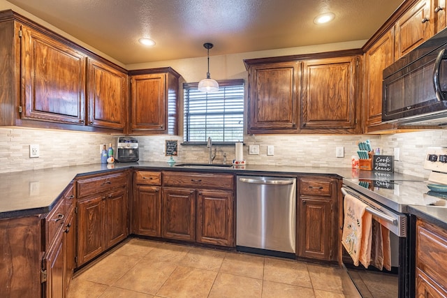 kitchen with dark countertops, appliances with stainless steel finishes, backsplash, and a sink