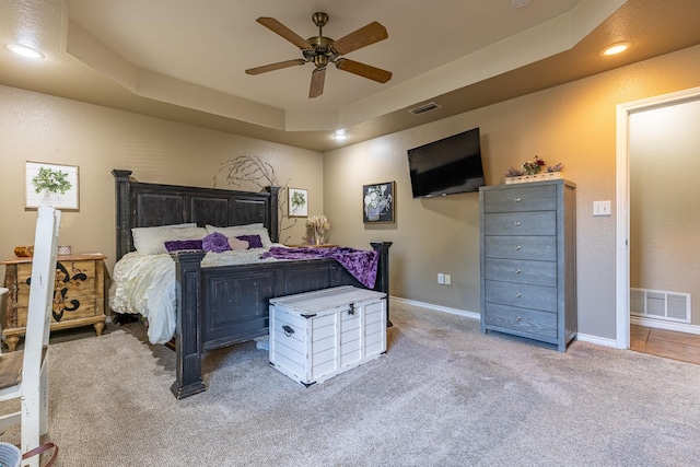 bedroom with baseboards, visible vents, carpet floors, and a tray ceiling