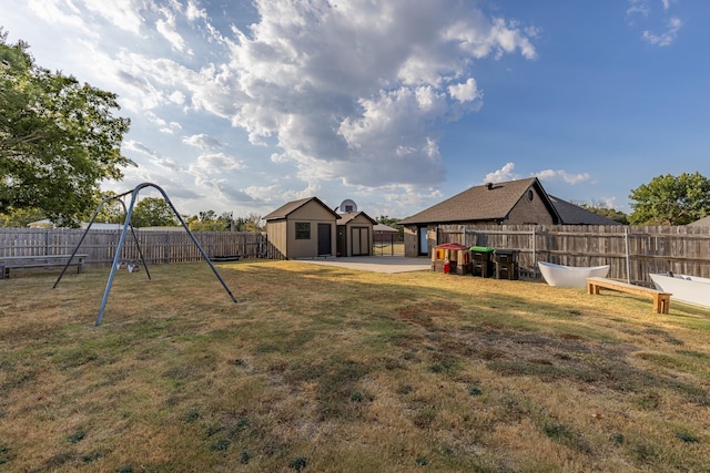 view of yard with an outbuilding, a patio, a playground, and a fenced backyard