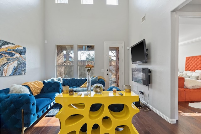 living room featuring visible vents, baseboards, a high ceiling, and wood finished floors
