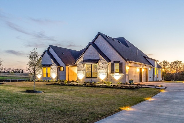 french country home with driveway, brick siding, a garage, a yard, and fence