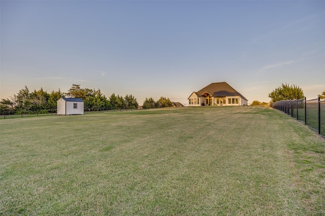 view of yard featuring a storage shed, fence, and an outbuilding