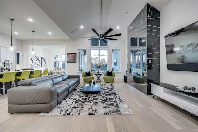 living area featuring high vaulted ceiling, recessed lighting, ceiling fan with notable chandelier, and wood finished floors