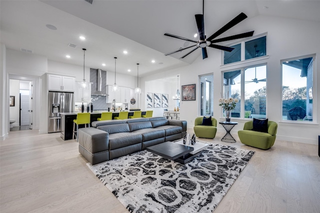 living area with high vaulted ceiling, light wood-style flooring, a ceiling fan, visible vents, and recessed lighting