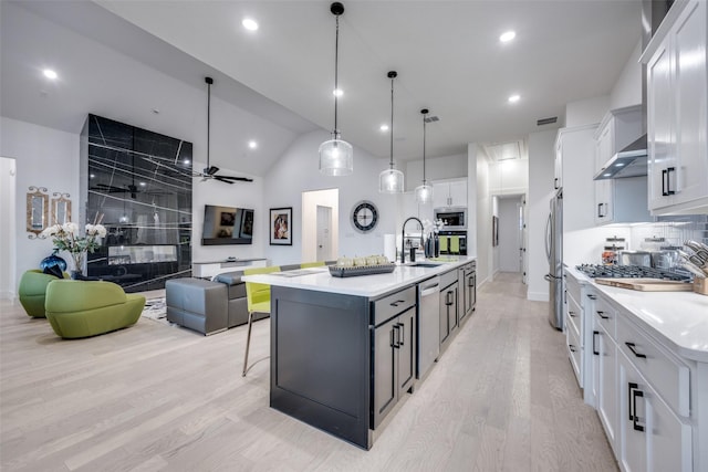 kitchen with white cabinets, a sink, light countertops, light wood-style floors, and stainless steel appliances