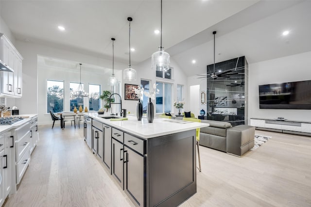 kitchen featuring white cabinets, light wood-style flooring, a sink, and a center island with sink