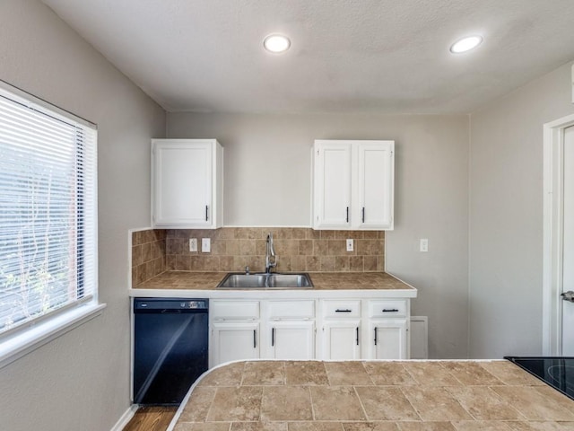 kitchen featuring black dishwasher, a sink, tasteful backsplash, white cabinets, and tile countertops