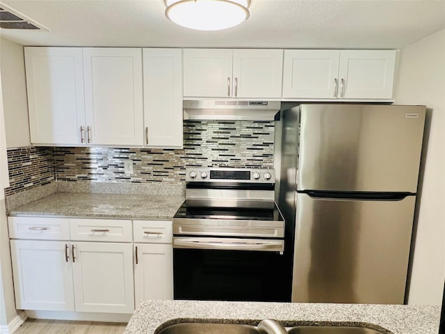 kitchen featuring stainless steel appliances, visible vents, white cabinetry, light stone countertops, and under cabinet range hood