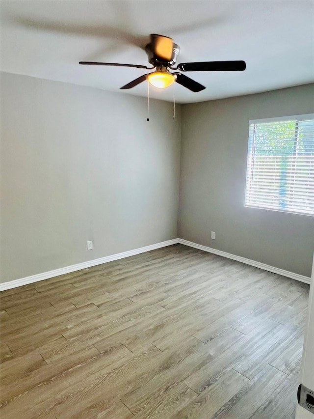 spare room featuring ceiling fan, baseboards, and wood finished floors