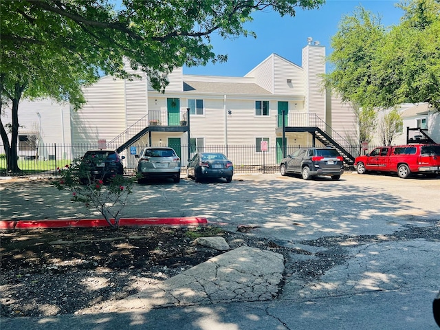 exterior space with uncovered parking, stairway, and fence