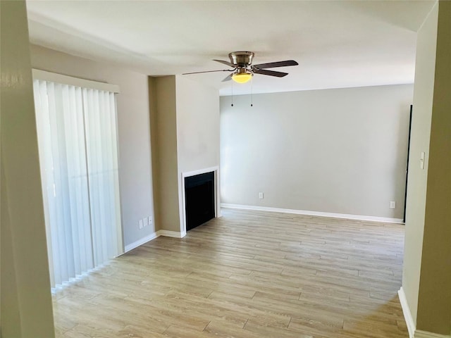 unfurnished living room with ceiling fan, baseboards, light wood-style floors, and a fireplace