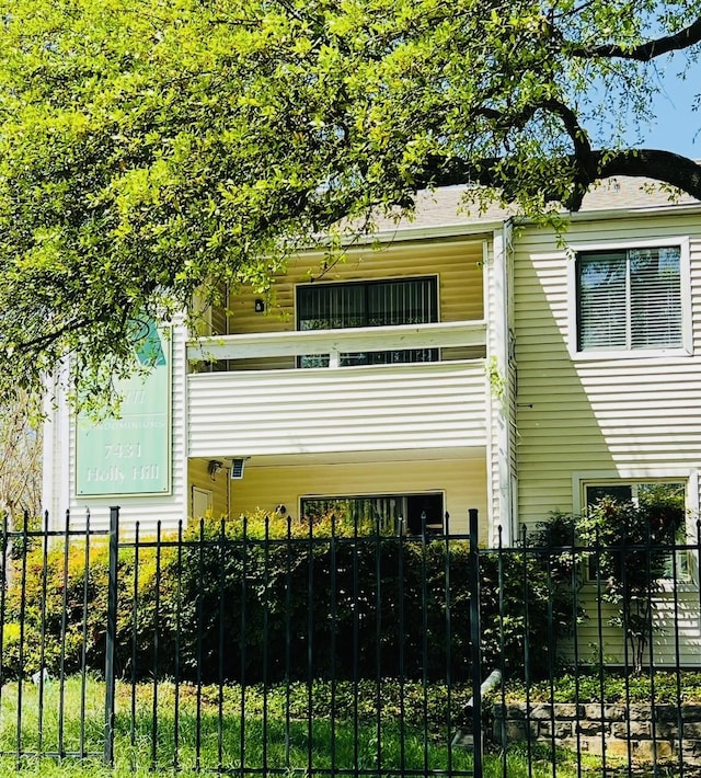 exterior space with a balcony and a fenced front yard