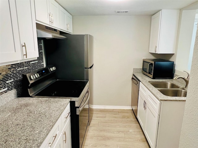 kitchen with a sink, decorative backsplash, stainless steel appliances, light wood-style flooring, and under cabinet range hood