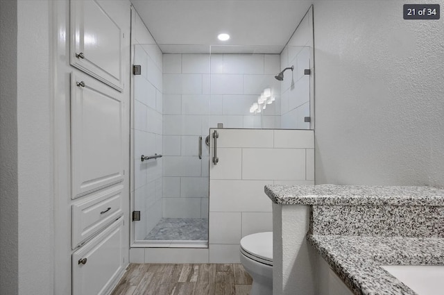 bathroom featuring a shower stall, toilet, vanity, and wood finished floors