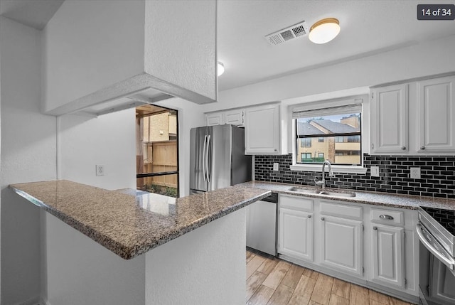 kitchen featuring a sink, visible vents, white cabinetry, decorative backsplash, and appliances with stainless steel finishes