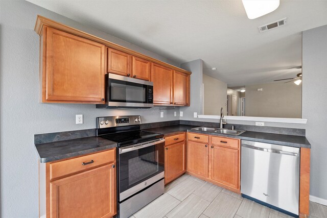 117 Independence Ave, Venus, TX 76084 - kitchen featuring appliances with stainless steel finishes, a sink, dark countertops, a ceiling fan, and a peninsula