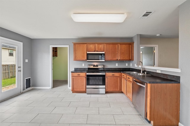 117 Independence Ave, Venus, TX 76084 - kitchen featuring a sink, stainless steel appliances, dark countertops, brown cabinets, and baseboards