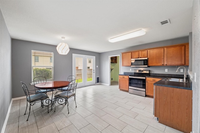 117 Independence Ave, Venus, TX 76084 - kitchen featuring stainless steel appliances, a sink, dark countertops, brown cabinets, and baseboards