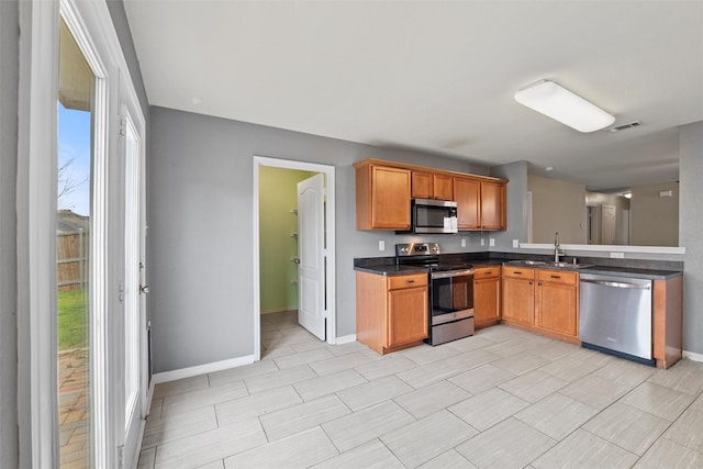 117 Independence Ave, Venus, TX 76084 - kitchen with appliances with stainless steel finishes, a sink, dark countertops, baseboards, and brown cabinetry