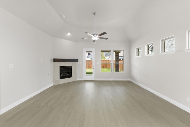 unfurnished living room with a tiled fireplace, baseboards, and wood finished floors