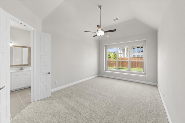 unfurnished bedroom with visible vents, vaulted ceiling, light carpet, a sink, and baseboards