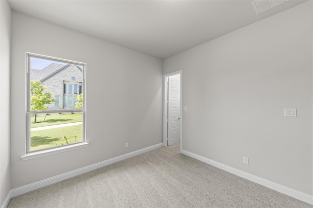 empty room with light colored carpet, baseboards, and visible vents