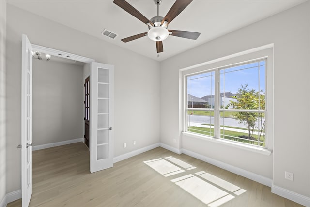 unfurnished room with visible vents, baseboards, ceiling fan, light wood finished floors, and french doors