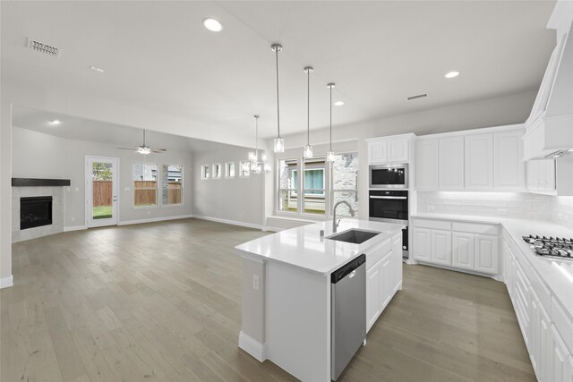 kitchen with a fireplace, backsplash, visible vents, stainless steel appliances, and a sink