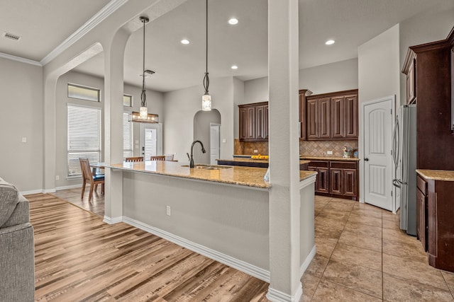 1109 Mount Ln, Rhome, TX 76078 - kitchen with a sink, freestanding refrigerator, arched walkways, a spacious island, and decorative backsplash