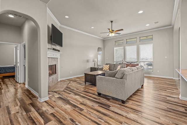 1109 Mount Ln, Rhome, TX 76078 - living area featuring arched walkways, crown molding, light wood-style floors, a ceiling fan, and a fireplace