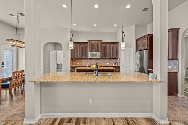 1109 Mount Ln, Rhome, TX 76078 - kitchen with appliances with stainless steel finishes, arched walkways, a sink, backsplash, and light stone counters