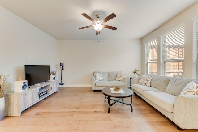 living room featuring baseboards, a ceiling fan, and light wood-style floors
