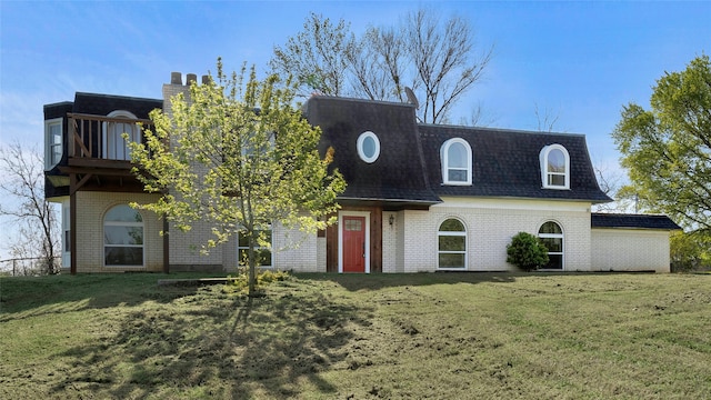 view of front of property with brick siding, a shingled roof, mansard roof, and a front yard