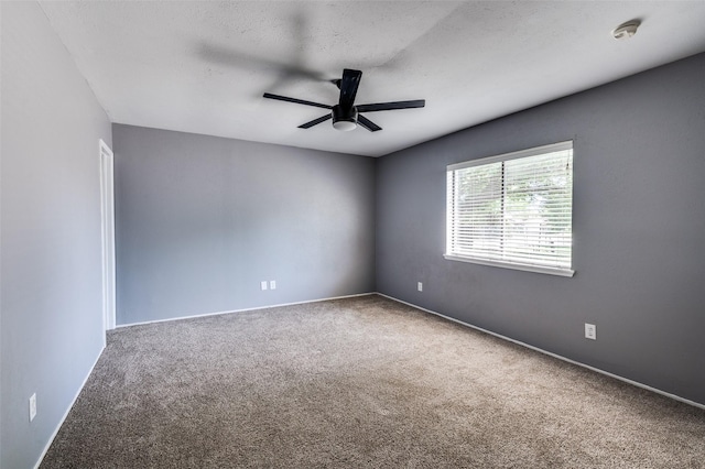 carpeted empty room with ceiling fan and baseboards