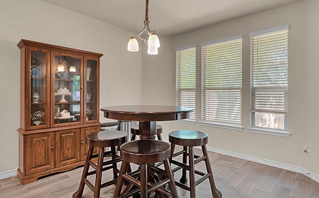 dining space featuring an inviting chandelier, baseboards, and wood finish floors