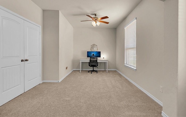 unfurnished office featuring light colored carpet, baseboards, and ceiling fan