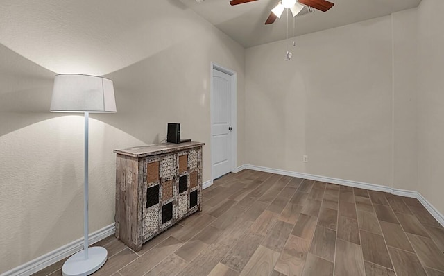 living area featuring baseboards, a ceiling fan, and wood tiled floor