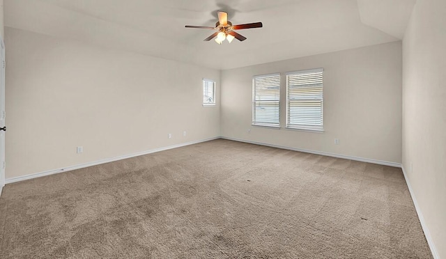carpeted spare room with ceiling fan and baseboards