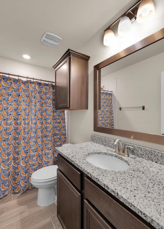 full bath featuring visible vents, a shower with curtain, toilet, vanity, and wood finished floors
