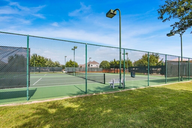 view of tennis court with fence and a lawn