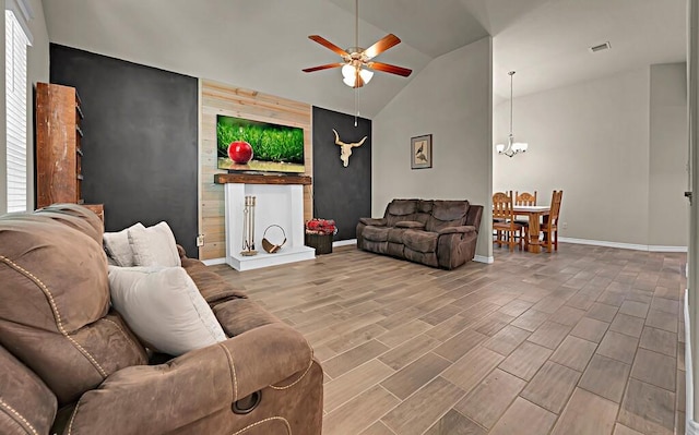 living area with an accent wall, visible vents, lofted ceiling, ceiling fan with notable chandelier, and wood finished floors