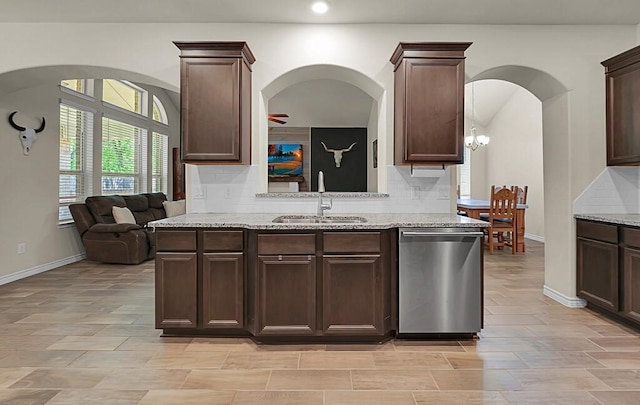 kitchen featuring a sink, tasteful backsplash, arched walkways, and dishwasher