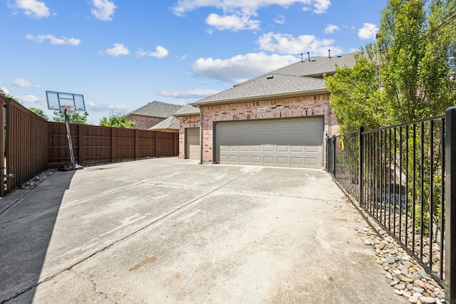 9892 Ranchero Dr, Frisco, TX 75033 - view of side of property featuring driveway, brick siding, a garage, fence, and a shingled roof