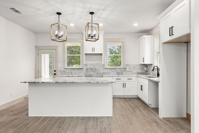 5703 Barkridge Dr, Granbury, TX 76048 - kitchen with light wood-style flooring, a center island, visible vents, decorative backsplash, and a sink