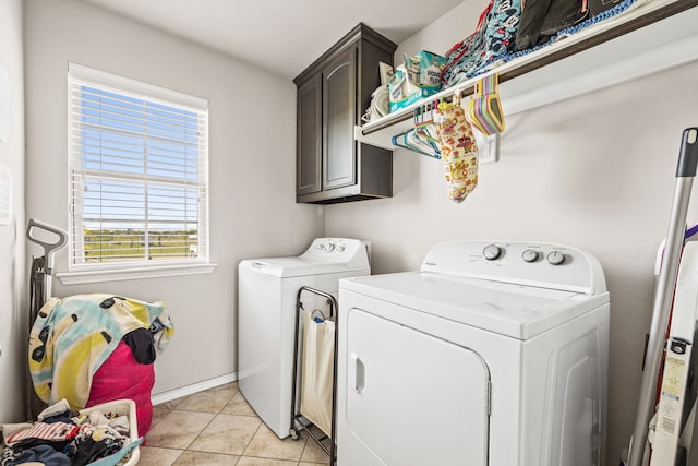 washroom with cabinet space, light tile patterned floors, independent washer and dryer, and baseboards