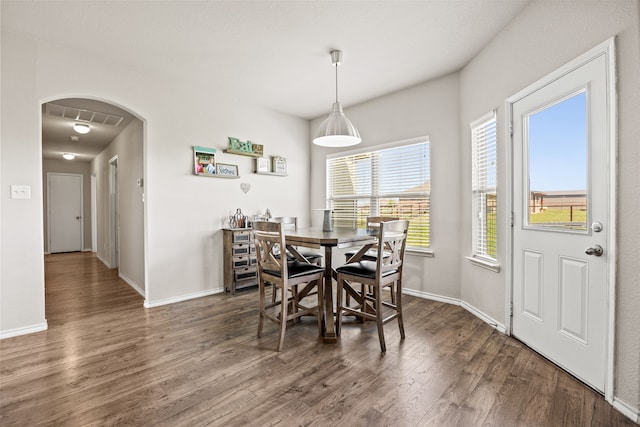 dining space featuring baseboards, arched walkways, and wood finished floors