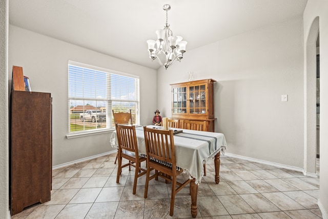 dining space with light tile patterned floors, baseboards, arched walkways, and a chandelier