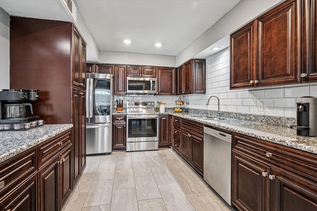 12550 Burninglog Ln, Dallas, TX 75243 - kitchen with light stone countertops, appliances with stainless steel finishes, a sink, recessed lighting, and decorative backsplash