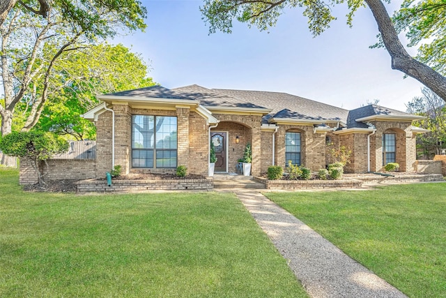 view of front of house featuring brick siding, a front lawn, and a shingled roof