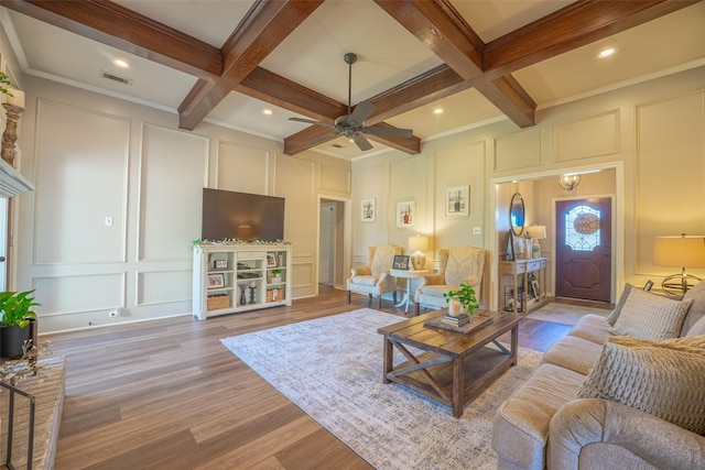 living room with a decorative wall, visible vents, coffered ceiling, and beamed ceiling